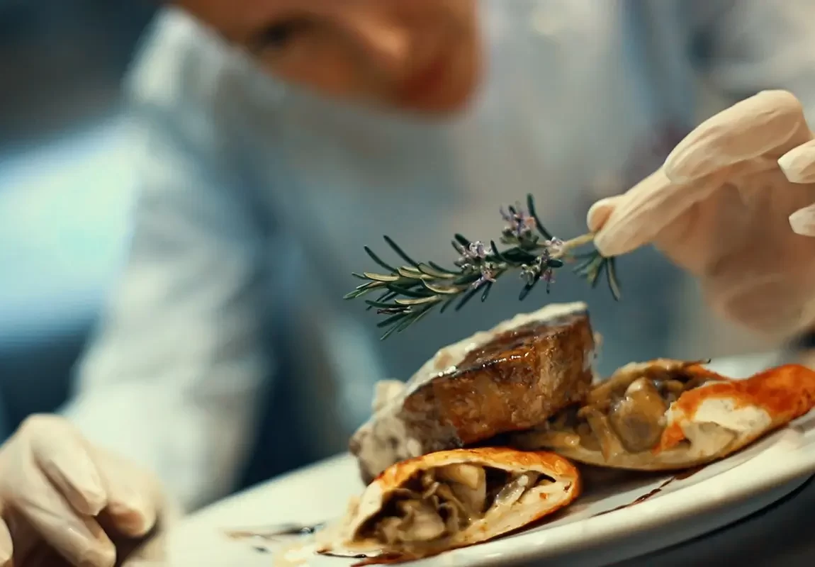 szef kuchni serwujący danie mięsne